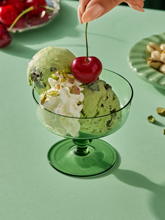 Pistasj-iskrem toppet med krem, nøtter og kirsebær