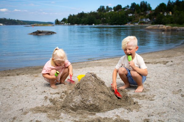 Barn spiser is og leker på strand